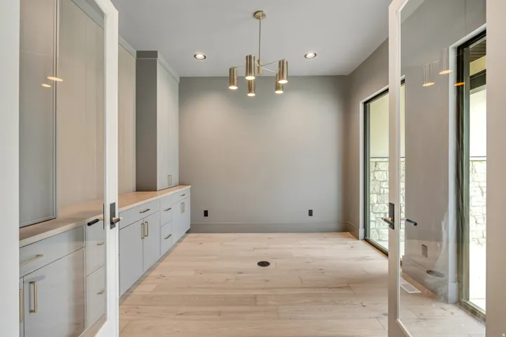 Built-in cabinetry with natural stone countertop, wood-finish flooring, recessed lighting, and a modern chandelier