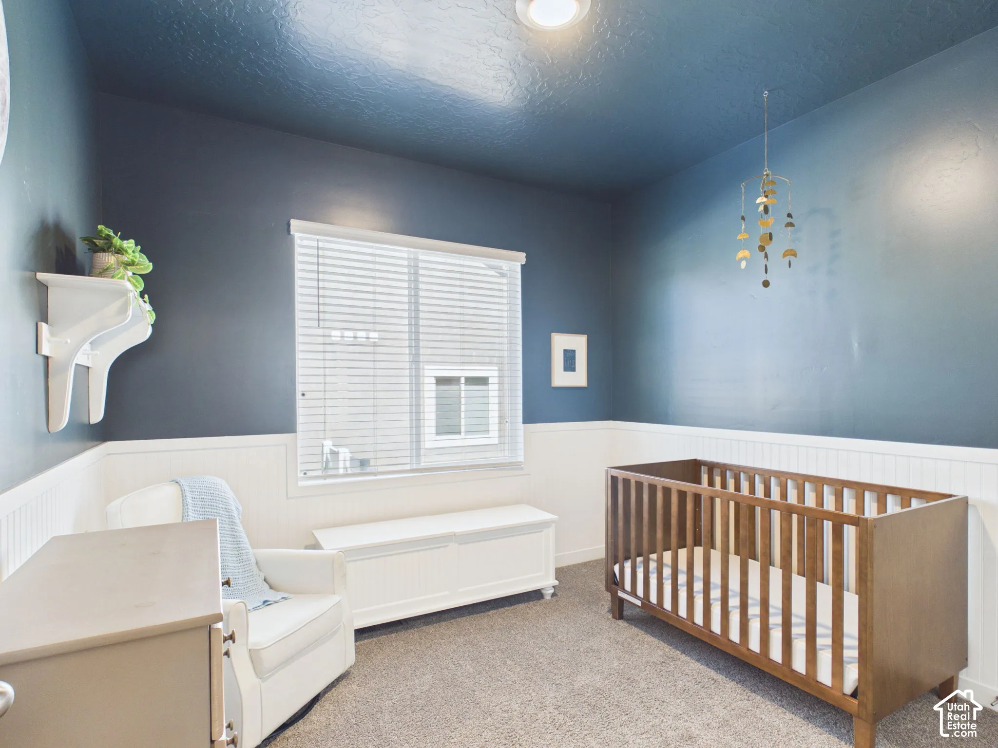 Window with horizontal blinds, overhead lighting, and two-tone wall treatment with wainscoting
