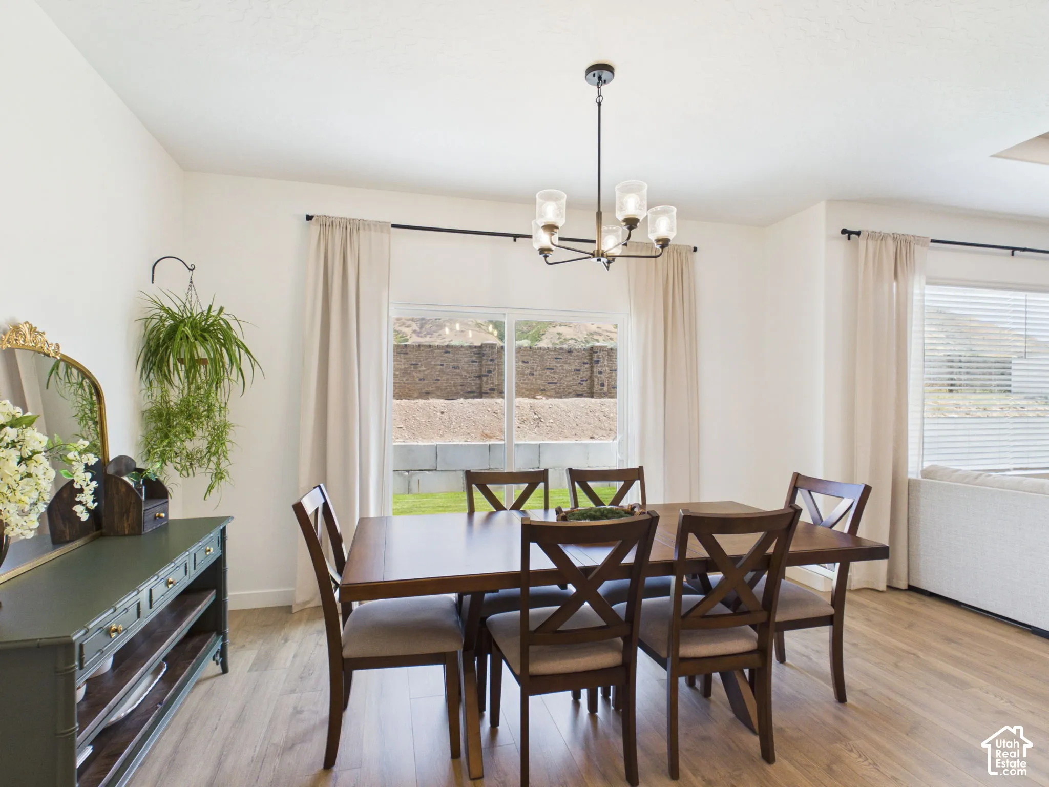 Open concept dining area featuring wood-finish flooring, a contemporary chandelier, and large windows with natural light