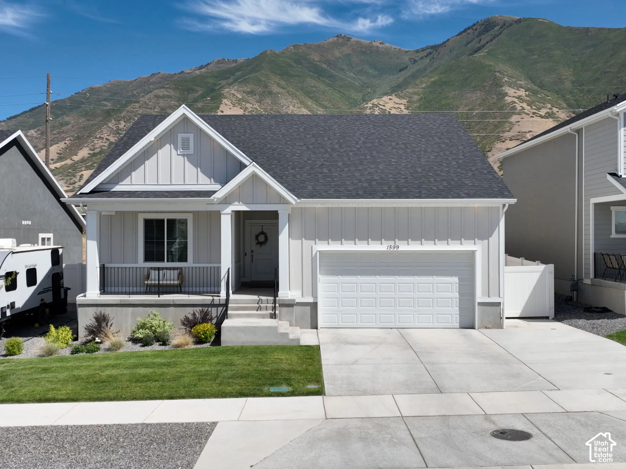 Modern farmhouse-style exterior with vertical siding, a covered front porch with black railing, an attached garage, and a concrete driveway