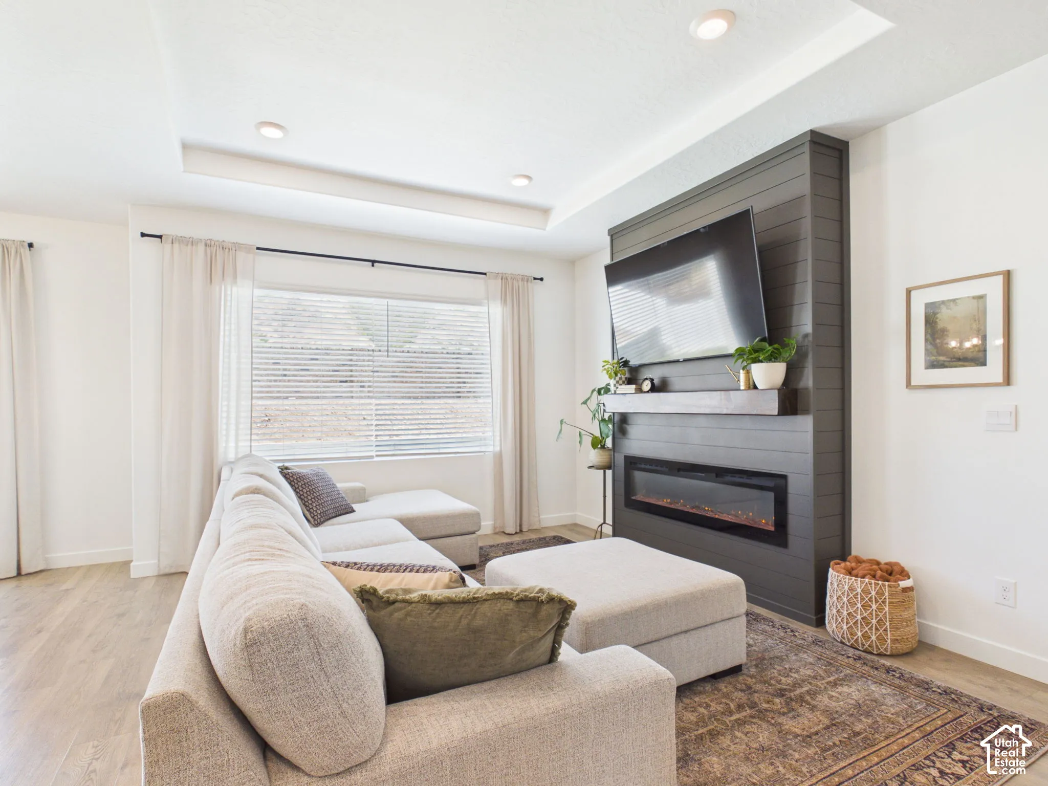 Recessed lighting illuminates the tray ceiling, complementing the shiplap-style fireplace with an integrated electric insert