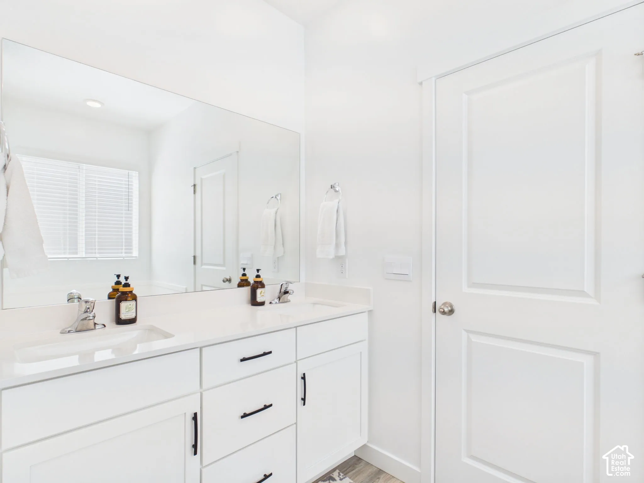 Dual vanity with integrated sinks, white cabinetry, and matte black hardware
