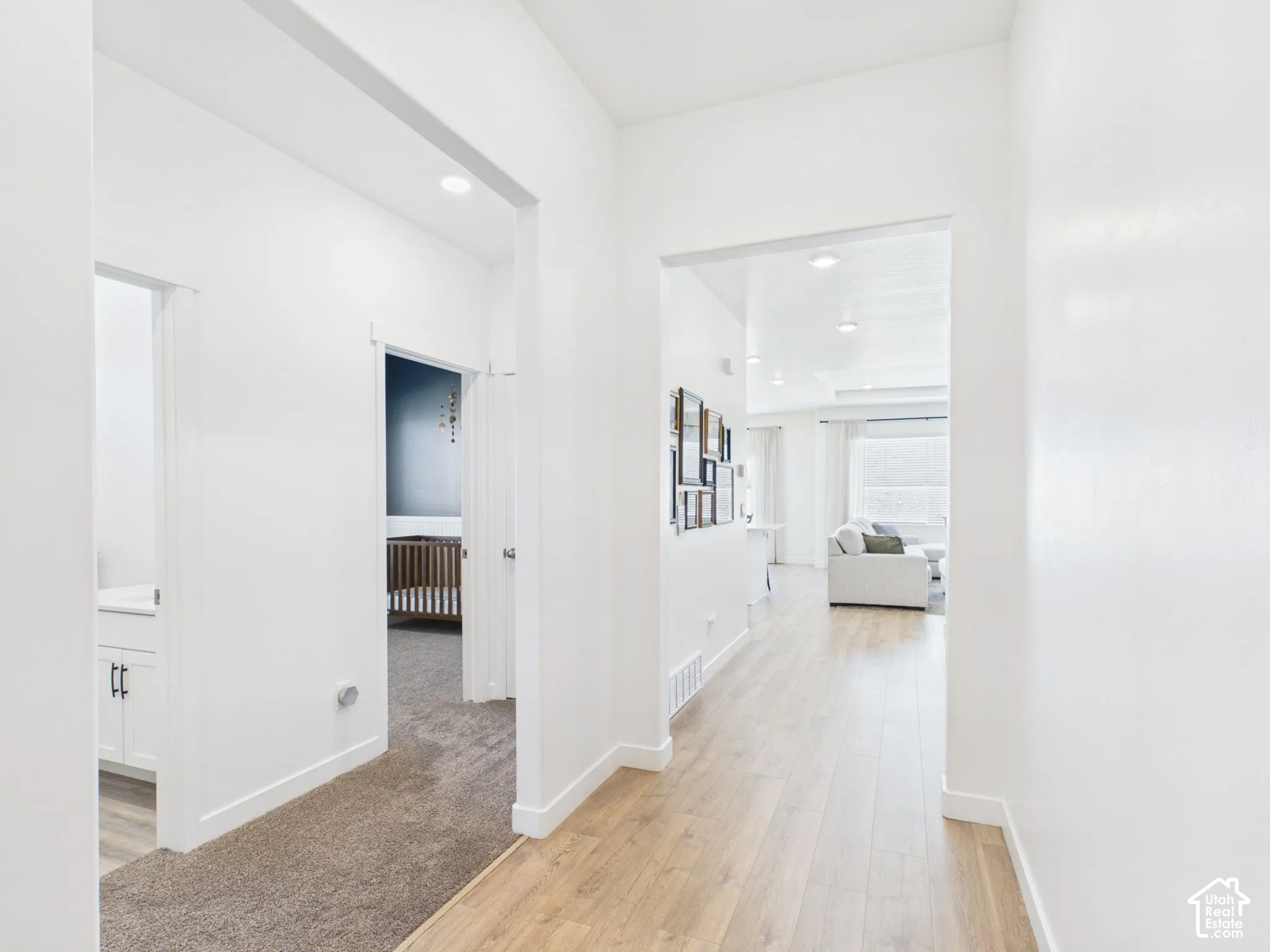 Hallway featuring wood-finish flooring, recessed lighting, and white walls