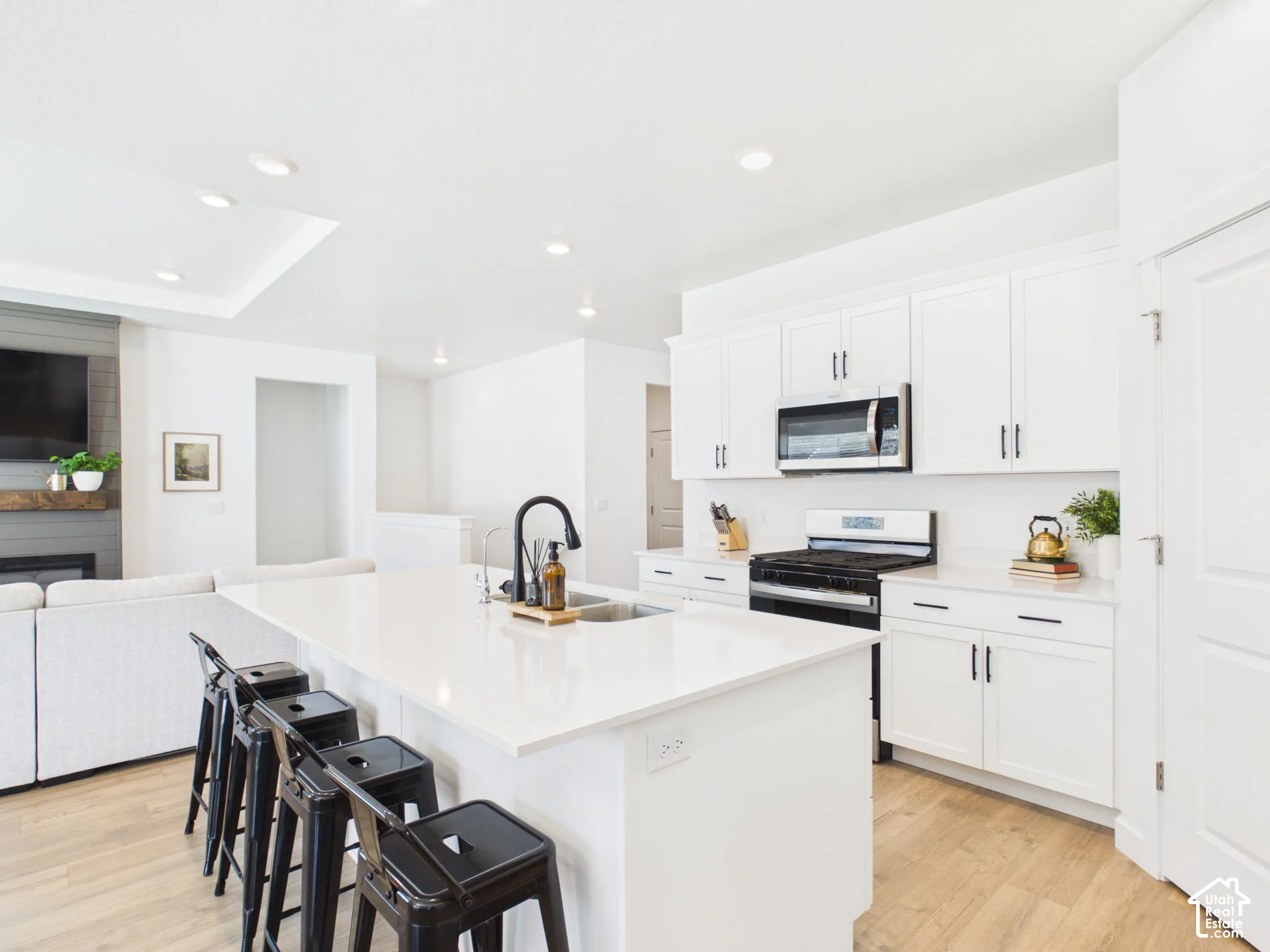 Spacious kitchen featuring white cabinetry, a large center island with a sink, stainless steel appliances, and recessed lighting