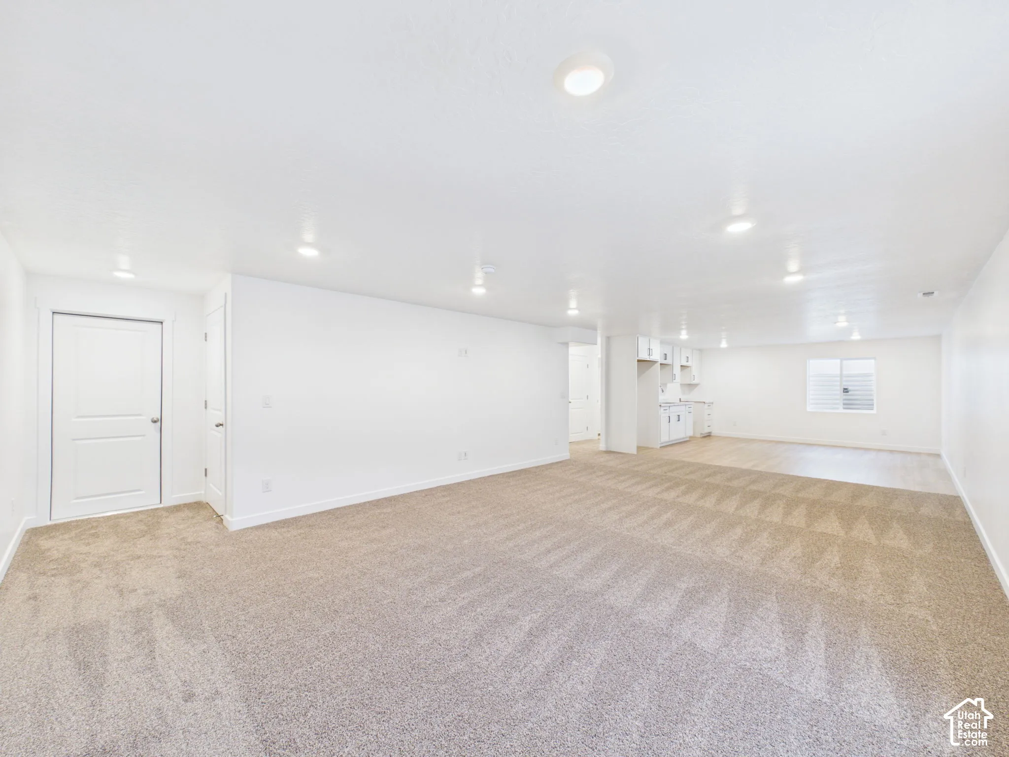 Recessed lighting, wall-to-wall carpeting, wood-finish flooring, white cabinetry, and white paneled doors