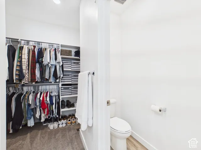 Compact water closet with a white toilet and wood-finish flooring