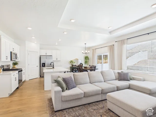 Recessed lighting illuminates the open-concept living space, featuring wood-finish flooring and a tray ceiling