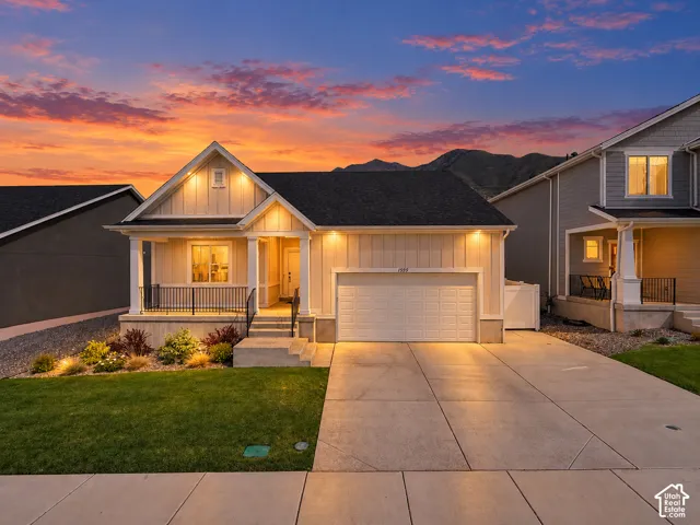 Contemporary home exterior featuring a front porch with black railings, a two-car garage, and a concrete driveway