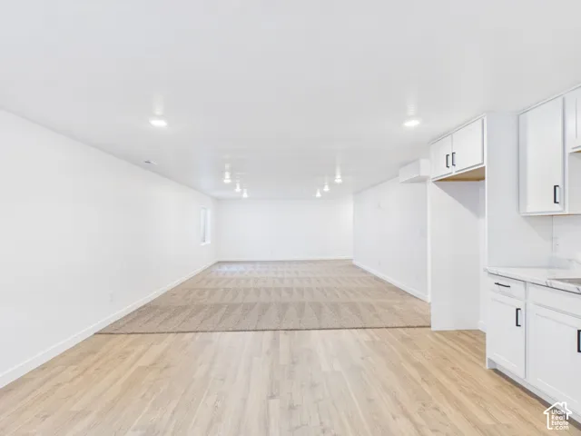 Recessed lighting illuminates the open-concept space featuring wood-finish flooring and a carpeted area
