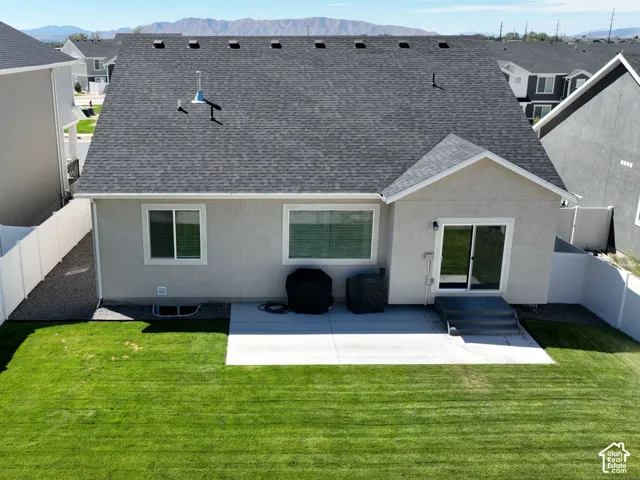 Expansive grassy yard with concrete patio, white privacy fencing, and sliding glass door access