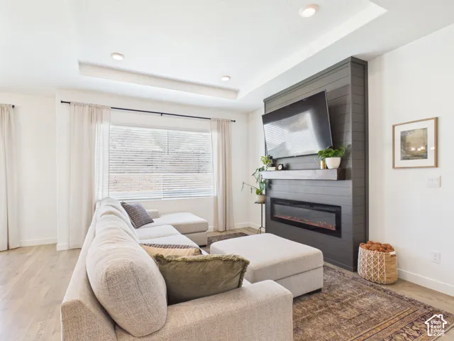 Recessed lighting illuminates the tray ceiling, complementing the shiplap-style fireplace with an integrated electric insert