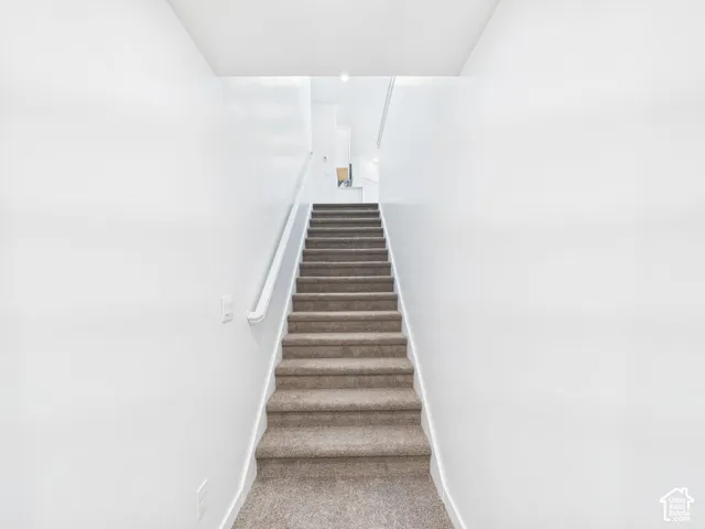 Carpeted staircase with a single handrail and light-toned walls