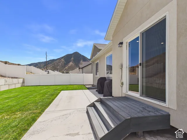 Spacious backyard retreat featuring a manicured lawn, concrete patio, and modern sliding glass doors opening from the residence