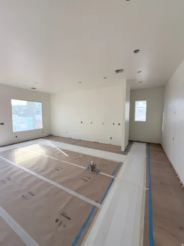 Recessed ceiling lighting, multiple large windows, and unfinished wood-finish flooring