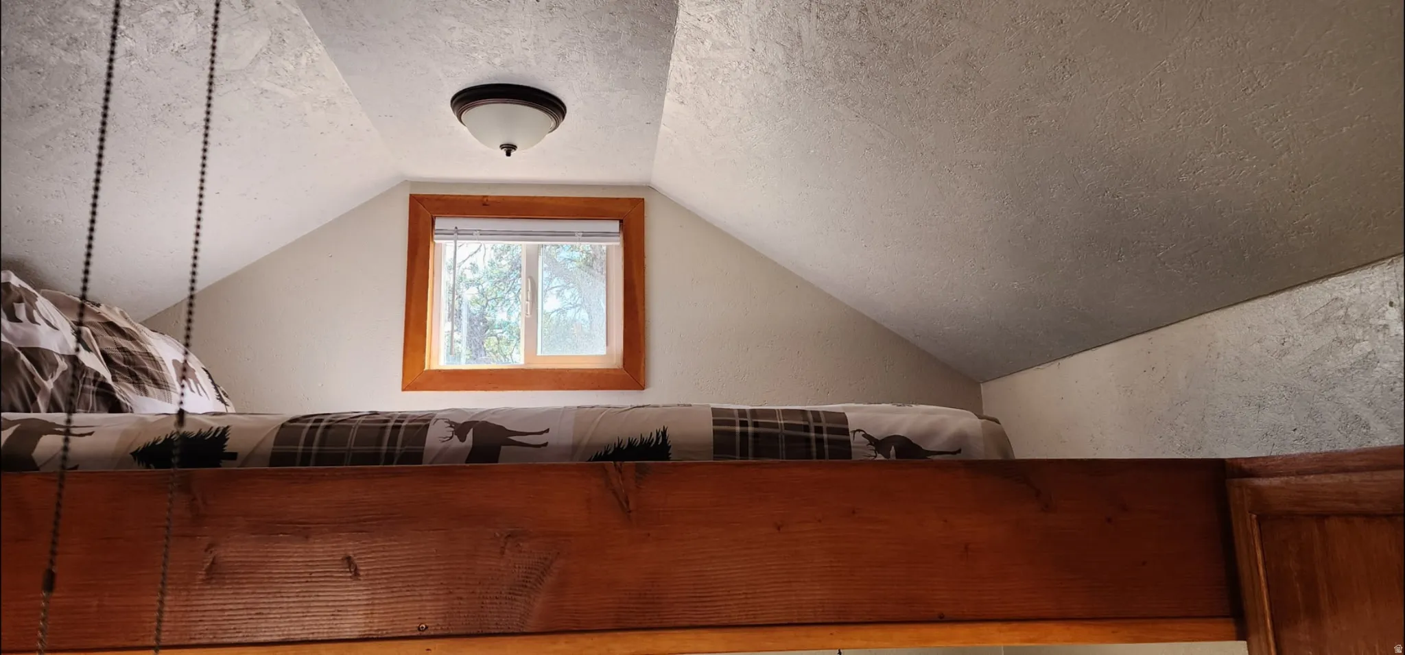 Built-in lofted platform with wood-finish framing, integrated window, and ceiling-mounted light fixture