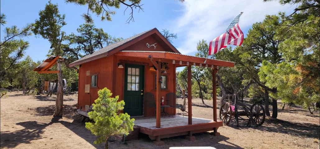 Wood-sided structure with a covered porch, wood plank decking, and a corrugated metal roof accent