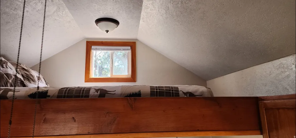 Built-in lofted platform with wood-finish framing, integrated window, and ceiling-mounted light fixture