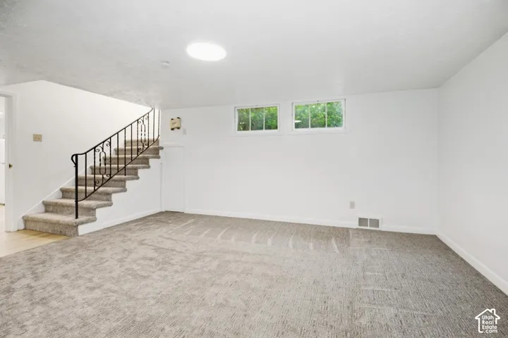Spacious room featuring new carpeting, white painted walls, and two multi-pane windows