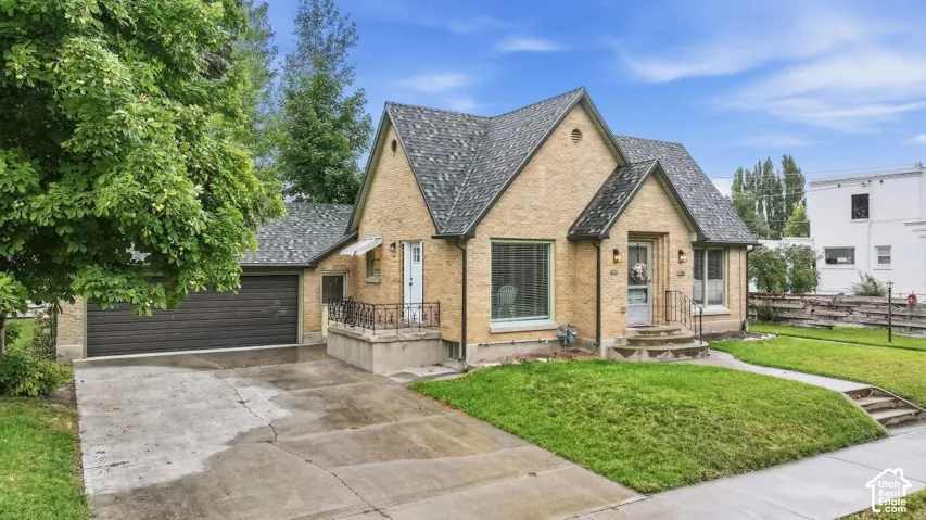 Brick exterior, gabled roofline, attached garage, concrete driveway, and front entryway with steps and railing