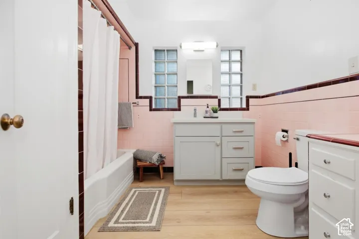 Bathroom featuring a white bathtub, pink tiled walls, a vanity with storage, and glass block windows