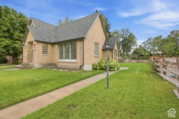 Brick exterior with a gabled roof, large front windows, a concrete walkway, and a fenced yard