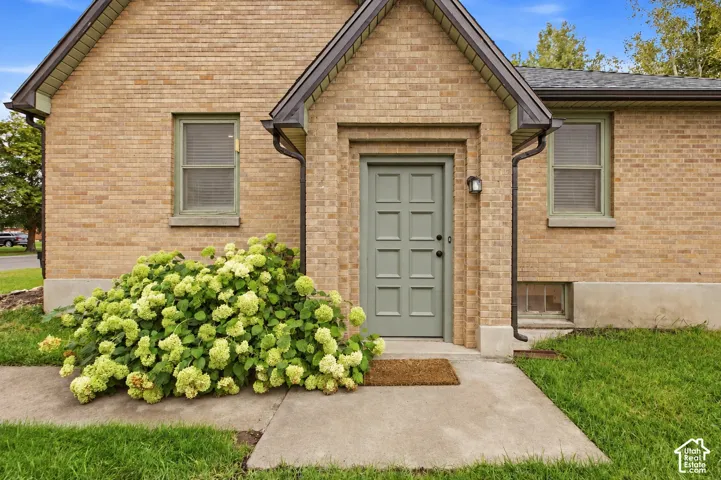 Brick exterior with a peaked entrance, panel-detailed entry door, and concrete walkway
