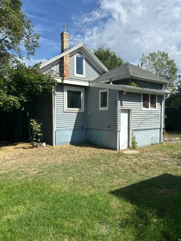 Exterior featuring light blue siding, a brick chimney, a gabled roofline, and an additional lower-level entrance