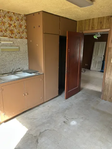 Double basin sink with base cabinetry, additional built-in cabinetry, wood-paneled wall, and a wood door frame