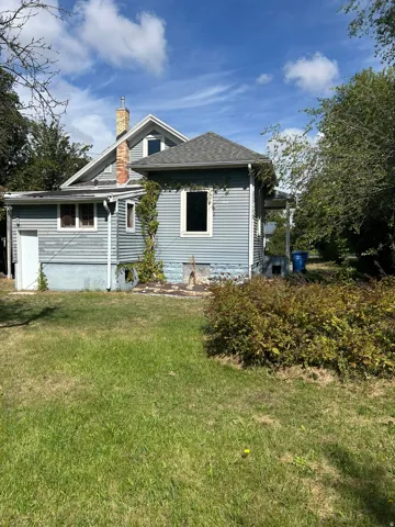 Blue siding exterior with a brick chimney and a pitched shingle roof