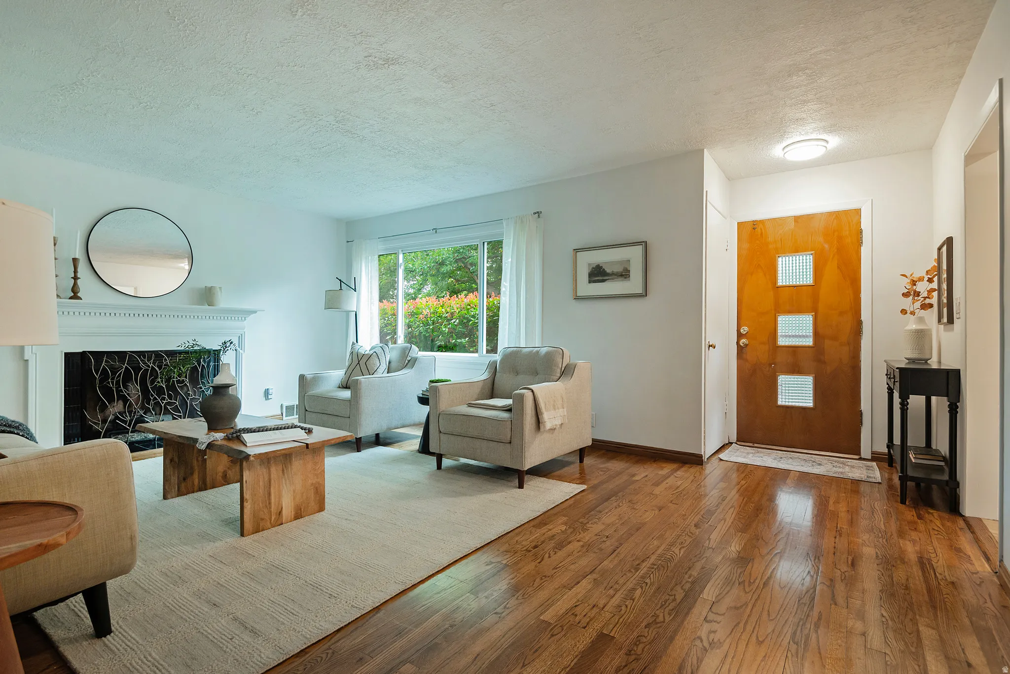 Hardwood flooring, white fireplace mantel, large window, wood-paneled door with frosted glass inserts, recessed lighting