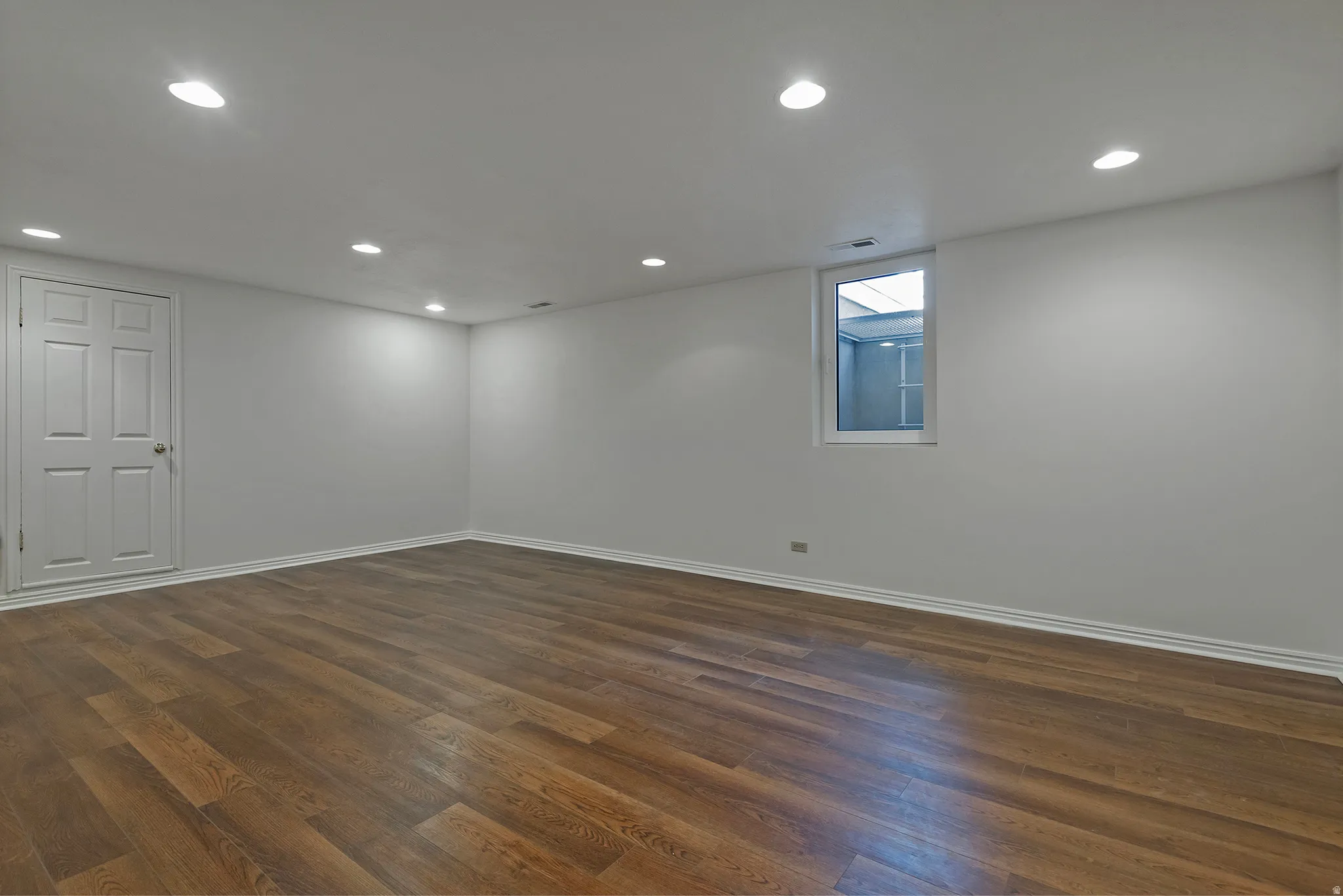 Wood flooring, recessed lighting, white trim, and a white interior door