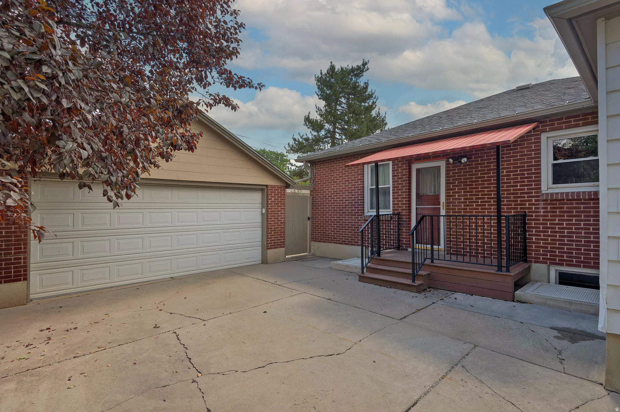 Brick exterior with a covered porch, metal awning, and detached two car garage