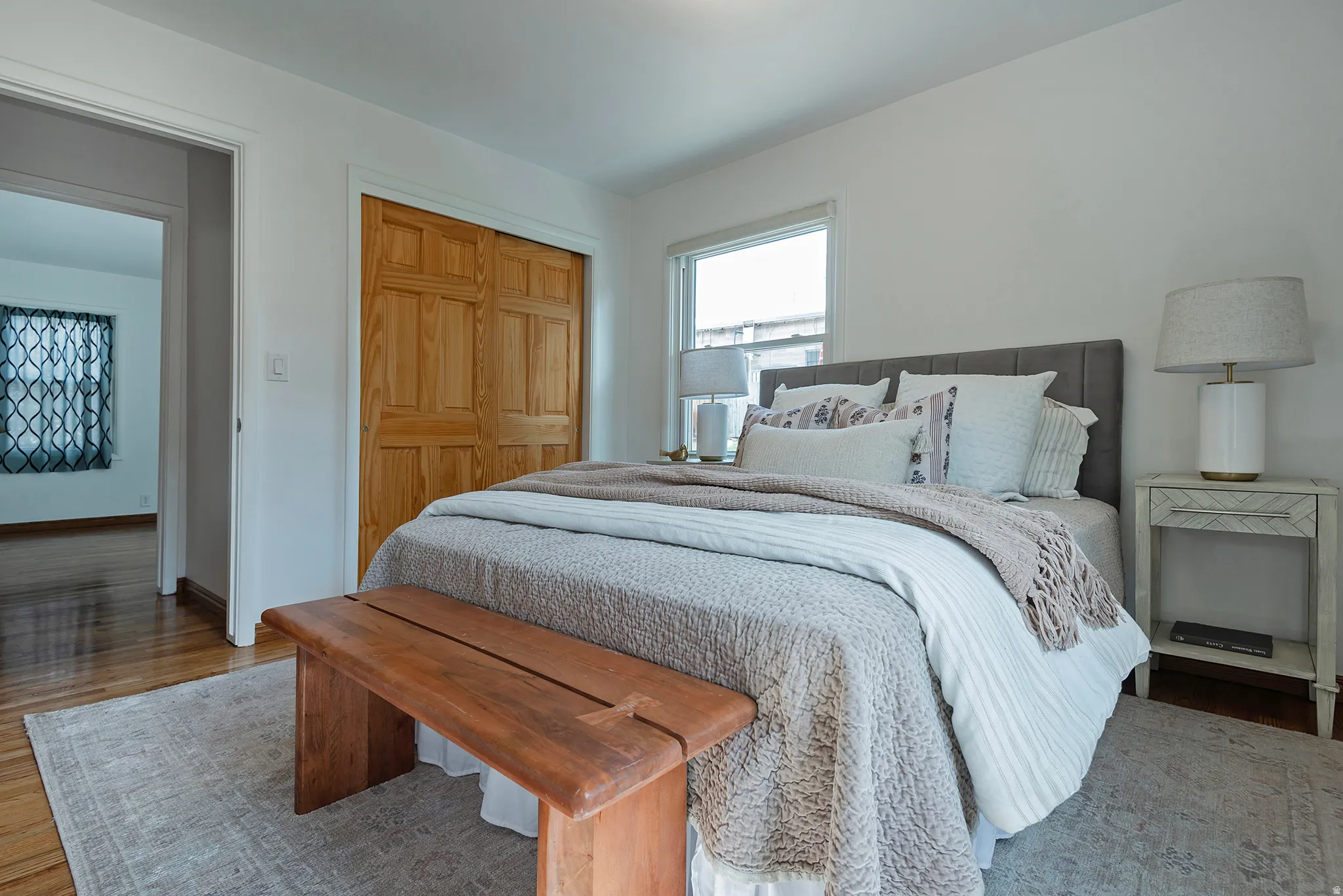 Hardwood flooring, light wood bi-fold closet doors, white walls, and large windows