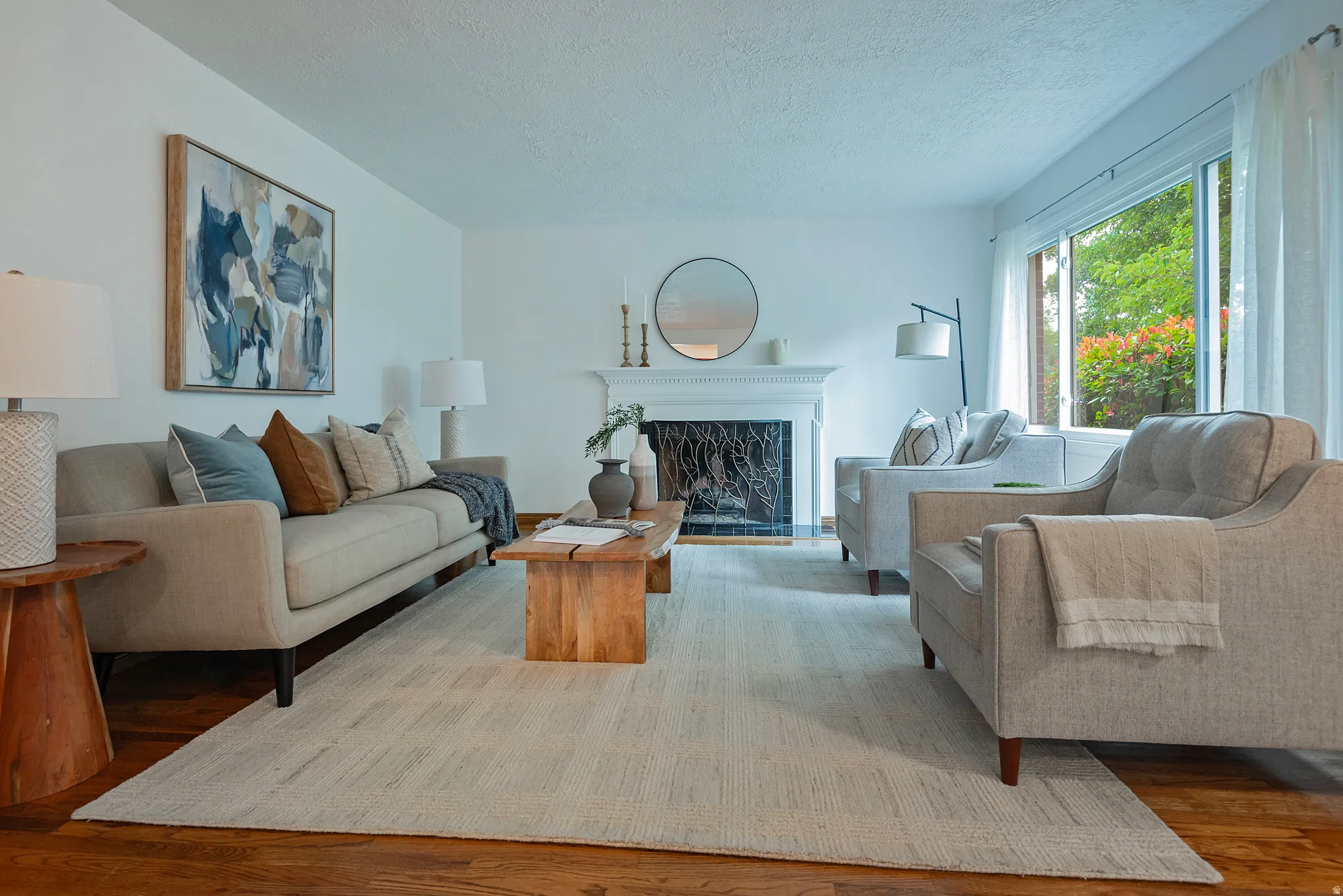 Hardwood flooring, white walls, and a fireplace with a white mantel