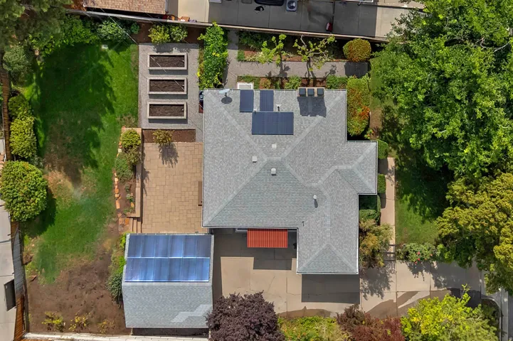 Gable roof with solar panels, paver patio, raised garden beds, and expansive lawn area