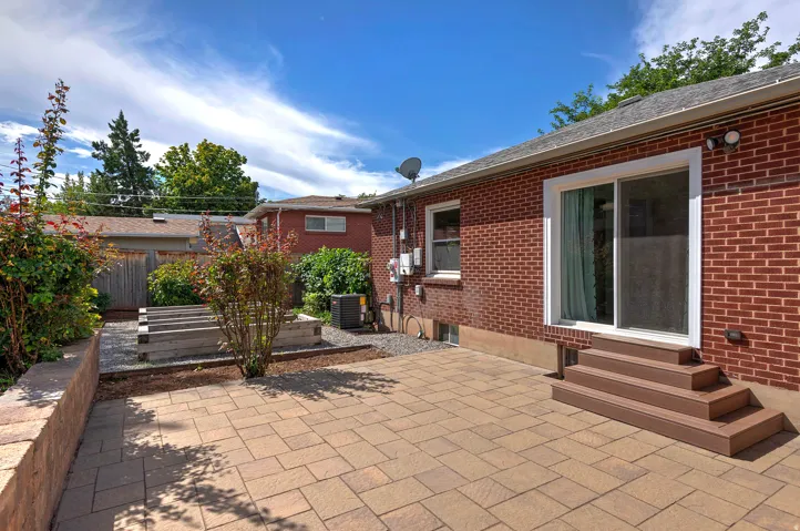 Brick exterior, paver patio, wood-finish steps, sliding glass door, raised garden beds