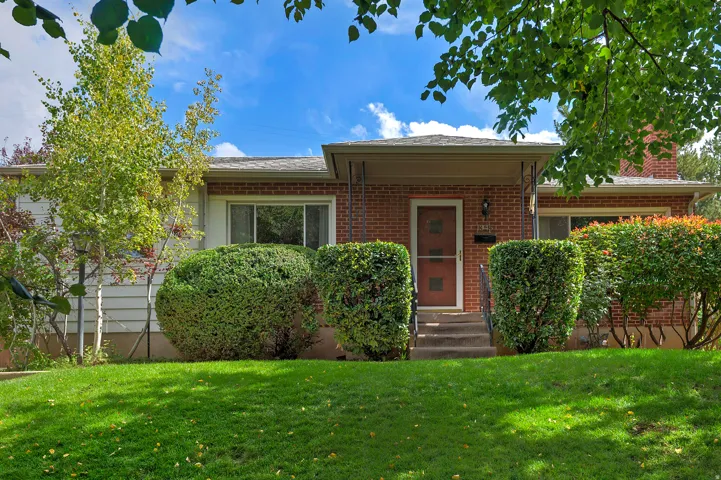 Brick exterior with a covered entry, concrete steps, and a lush green lawn