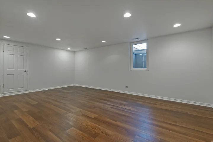 Wood flooring, recessed lighting, white trim, and a white interior door