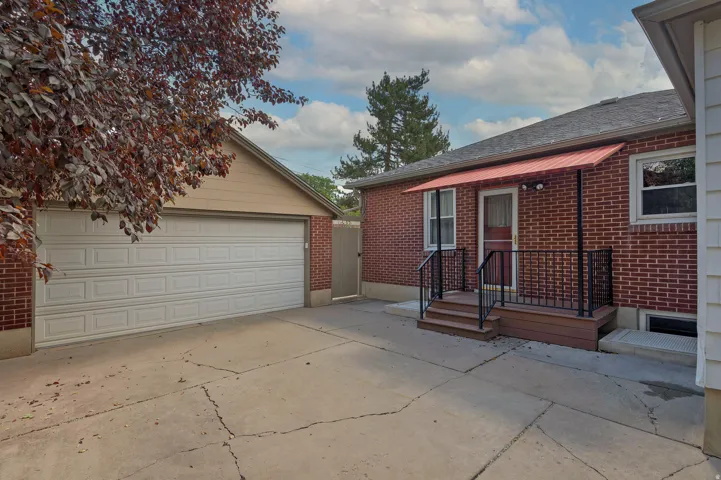 Brick exterior with a covered porch, metal awning, and detached two car garage