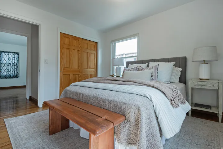 Hardwood flooring, light wood bi-fold closet doors, white walls, and large windows
