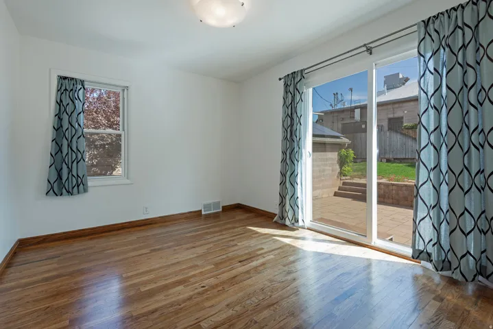 Wood flooring, white walls, large sliding glass door, single window, and a flush mount ceiling light