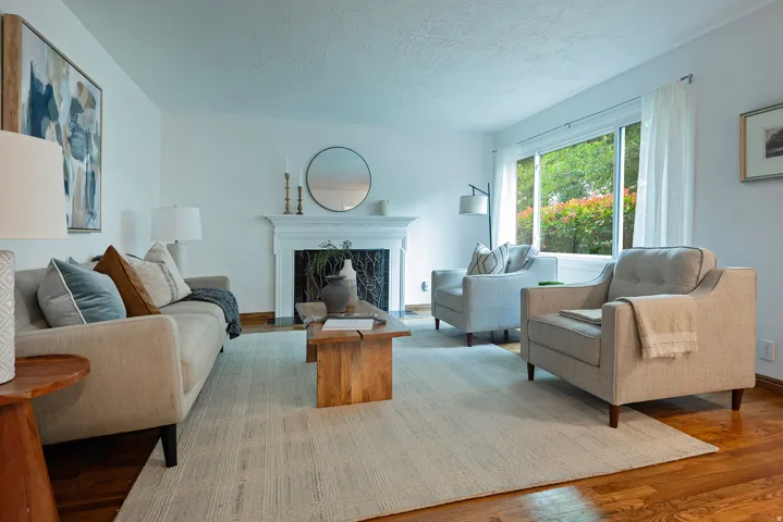 Wood flooring, white wall finishes, and a traditional fireplace with a white mantle