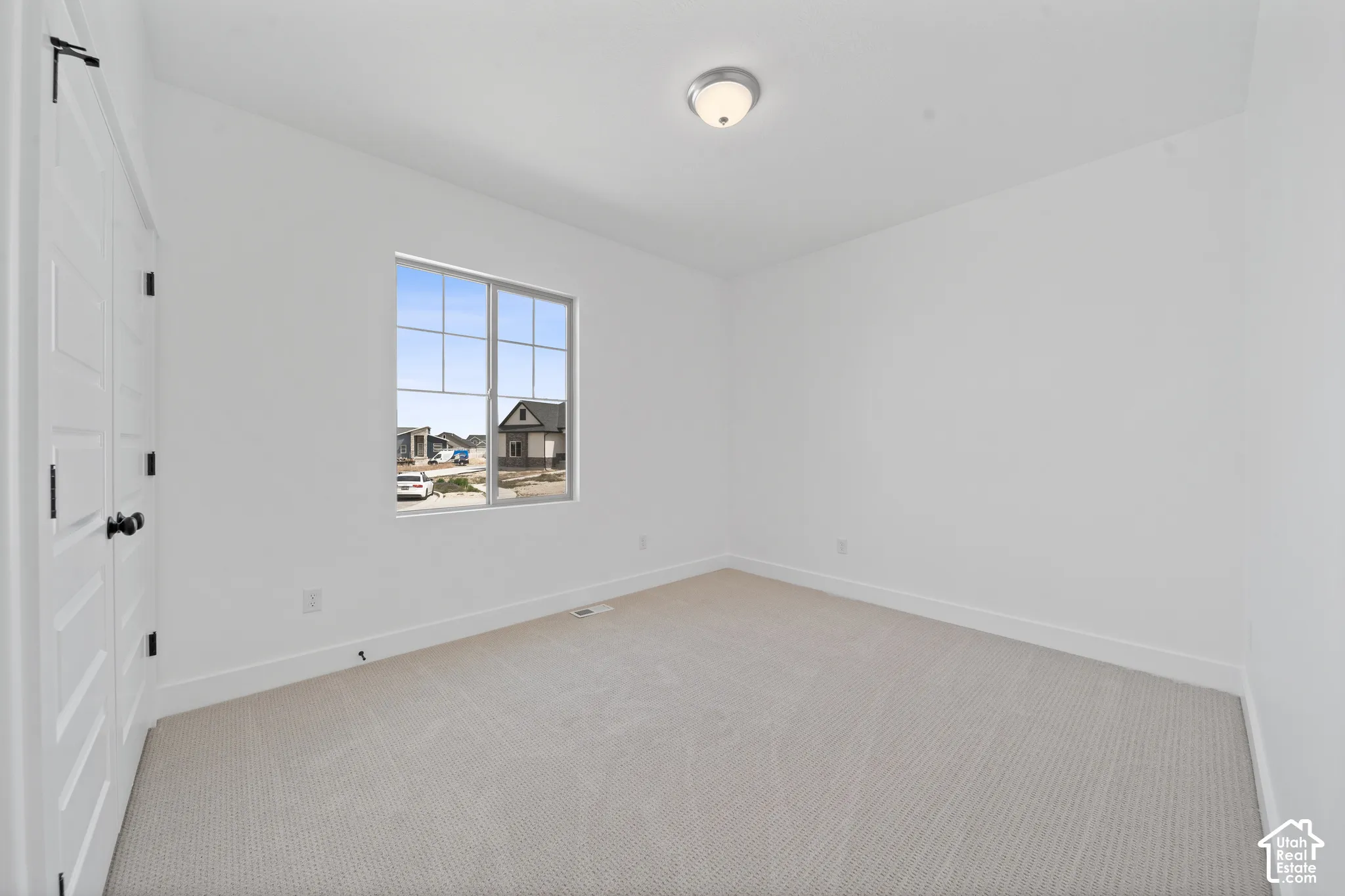 Crisp white walls, neutral carpeting, and a window with grid patterns