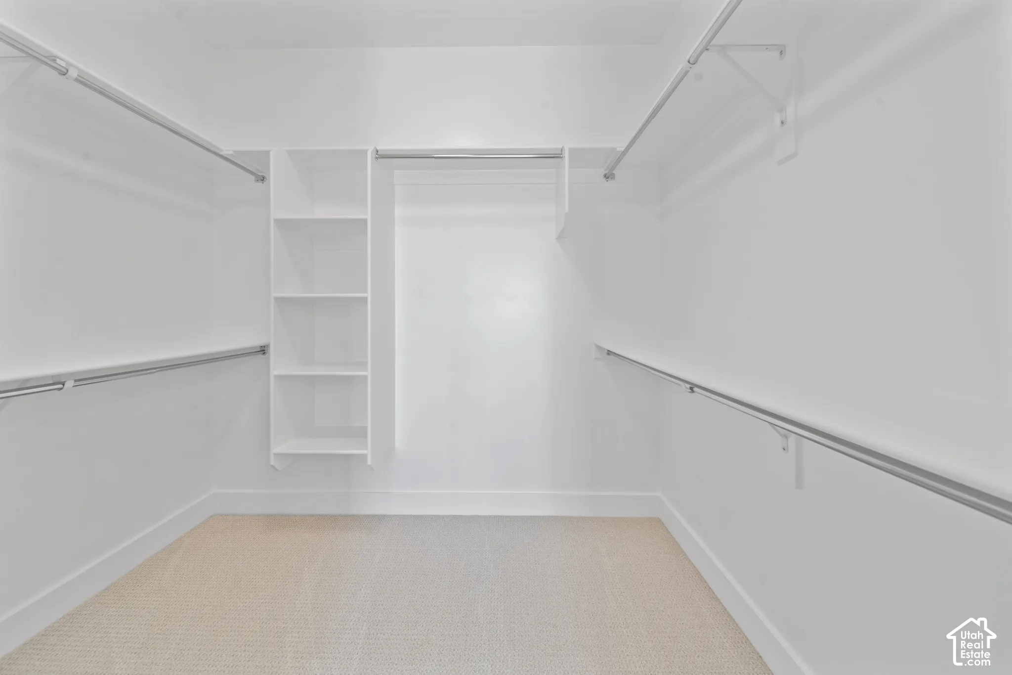 Spacious walk-in closet featuring built-in shelving, multiple hanging rods, and light-colored carpet