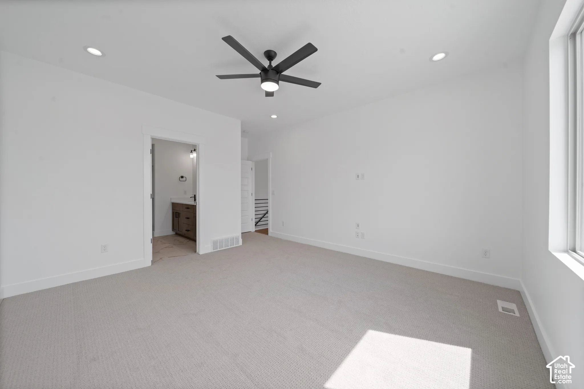 Spacious room featuring light-colored carpeting, recessed lighting, a modern ceiling fan, and a large window