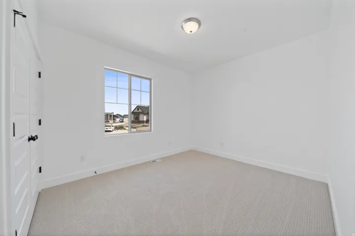 Crisp white walls, neutral carpeting, and a window with grid patterns