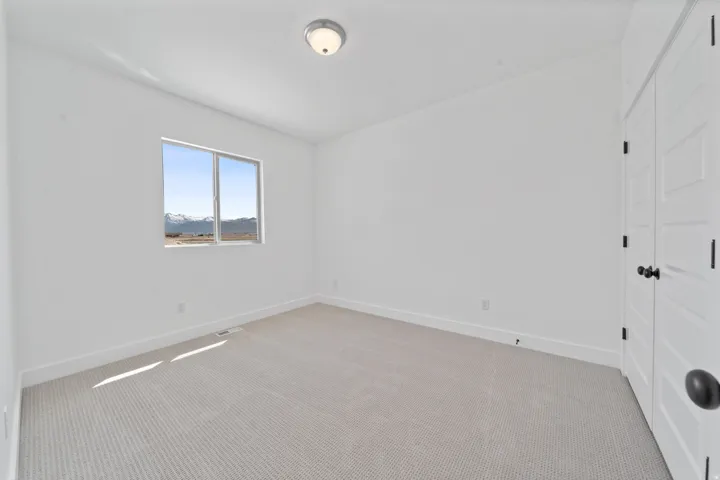 Bright room featuring neutral carpeting, a large window with mountain scenery, and white paneled doors with black hardware
