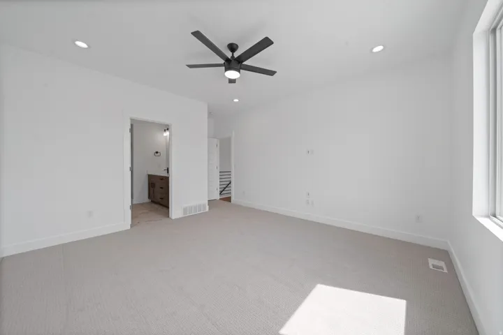 Spacious room featuring light-colored carpeting, recessed lighting, a modern ceiling fan, and a large window