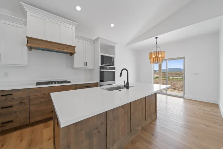 Kitchen featuring a center island with solid surface countertop, wood-finish cabinetry, white upper cabinetry, and a black faucet