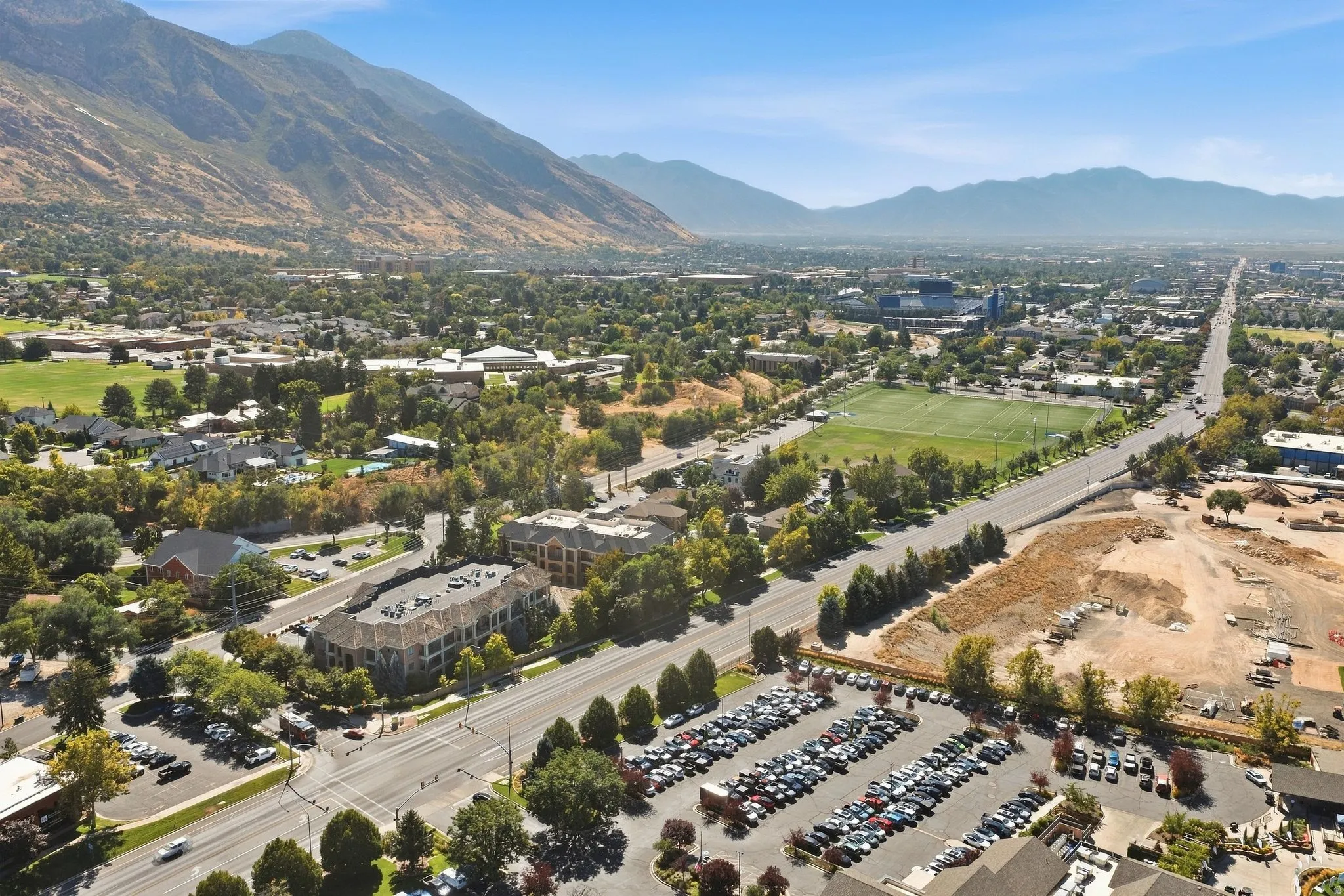 Expansive surrounding area featuring mature trees, mountain backdrop, paved roads, and developed properties with parking areas